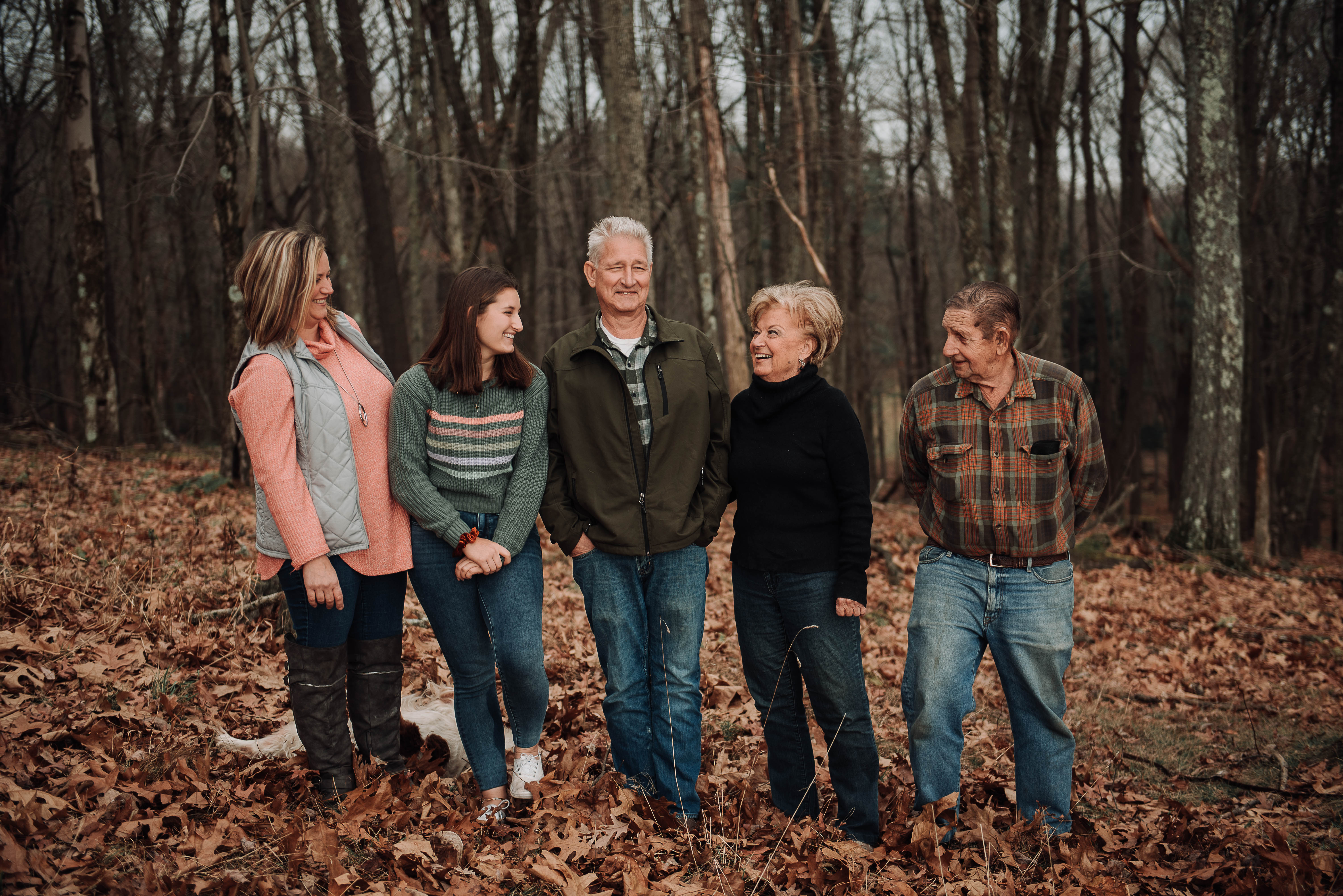 A multi-generational family stands in fallen leaves on their family land